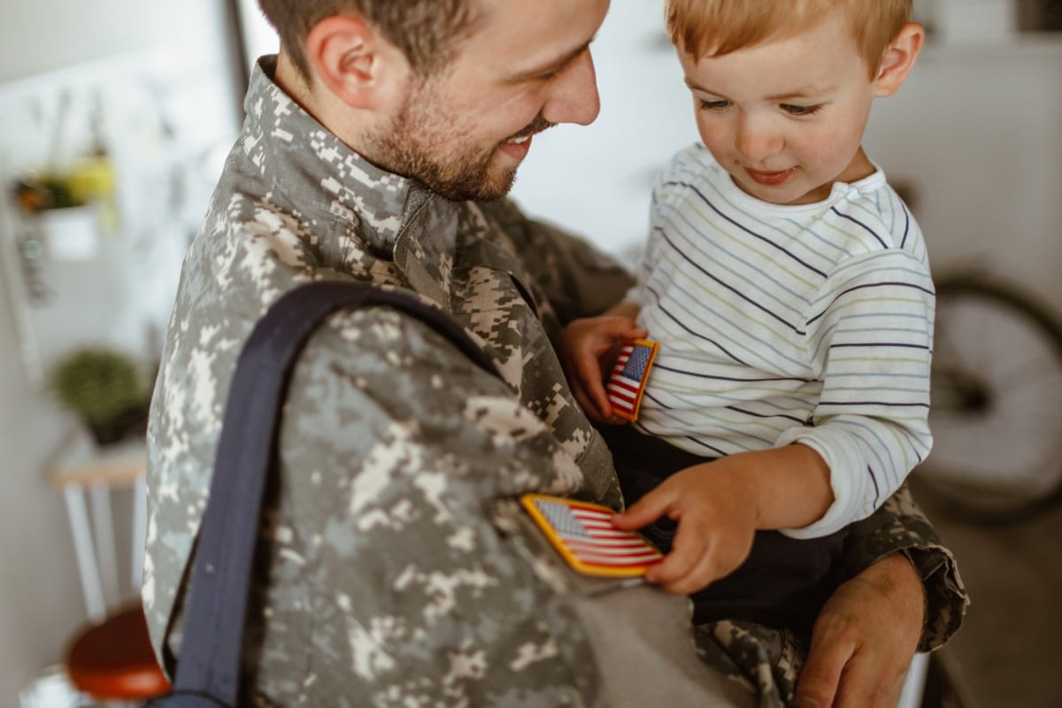 Dad in uniform holding toddler son and smiling